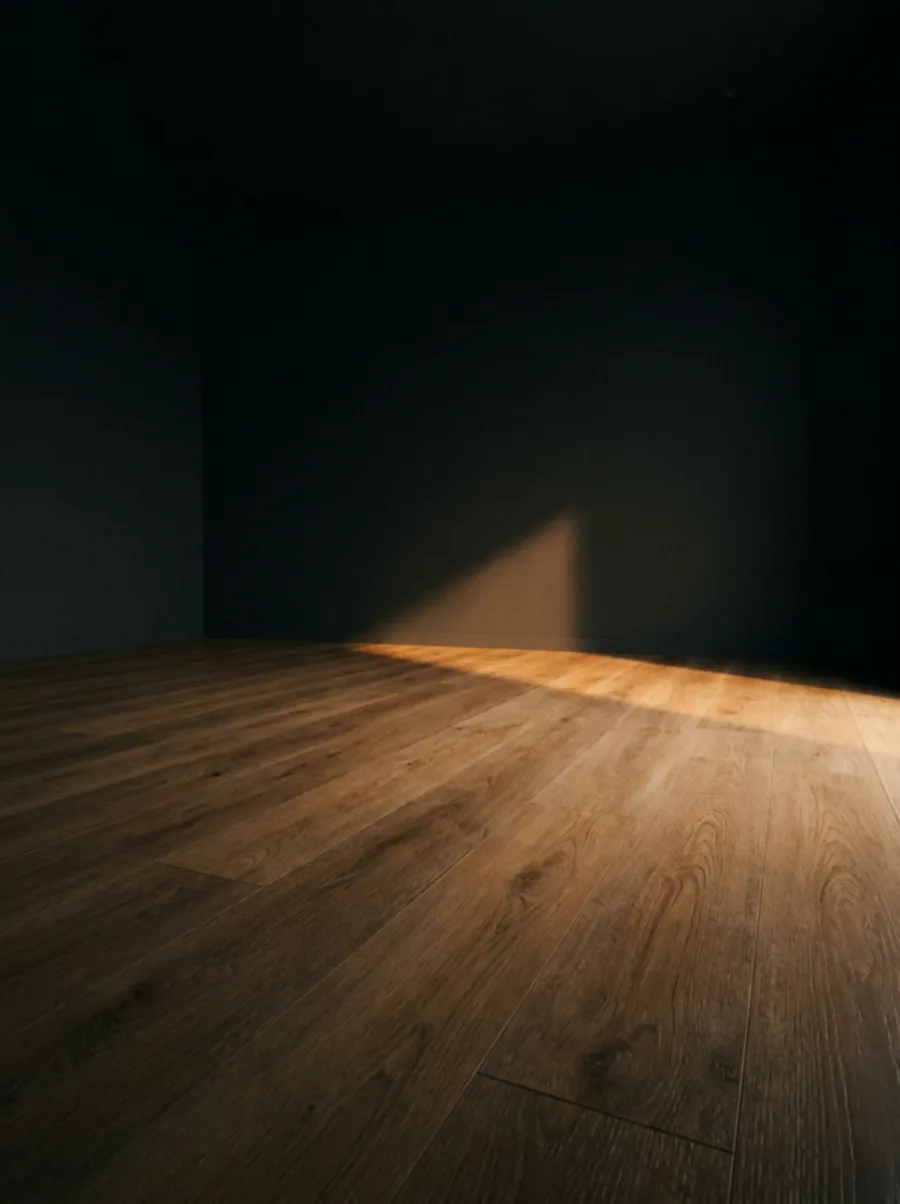 Wide plank wood-look porcelain tile in a dark living room, camera pushing slowly across the grain as a low beam of warm light crosses it